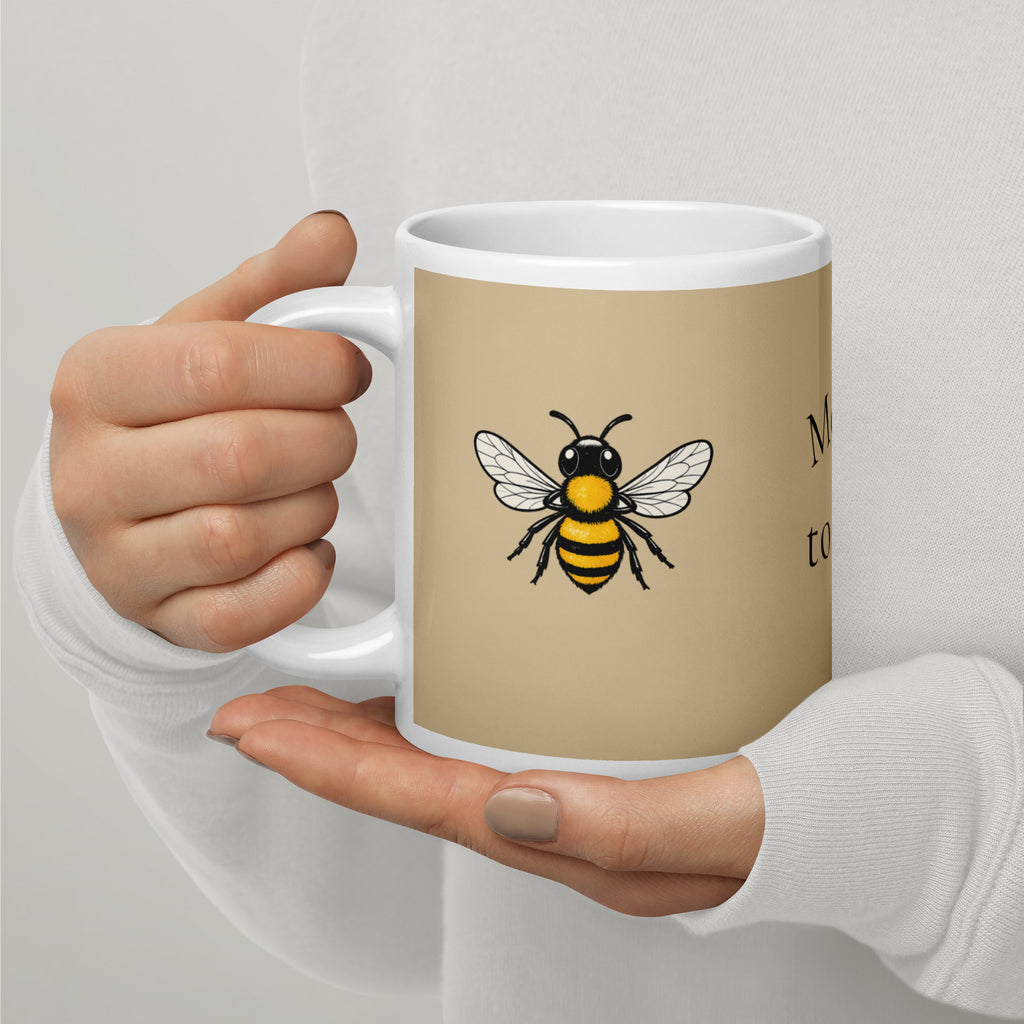 Beige ceramic mug with white handle and rim, yellow-and-black bee graphic on side