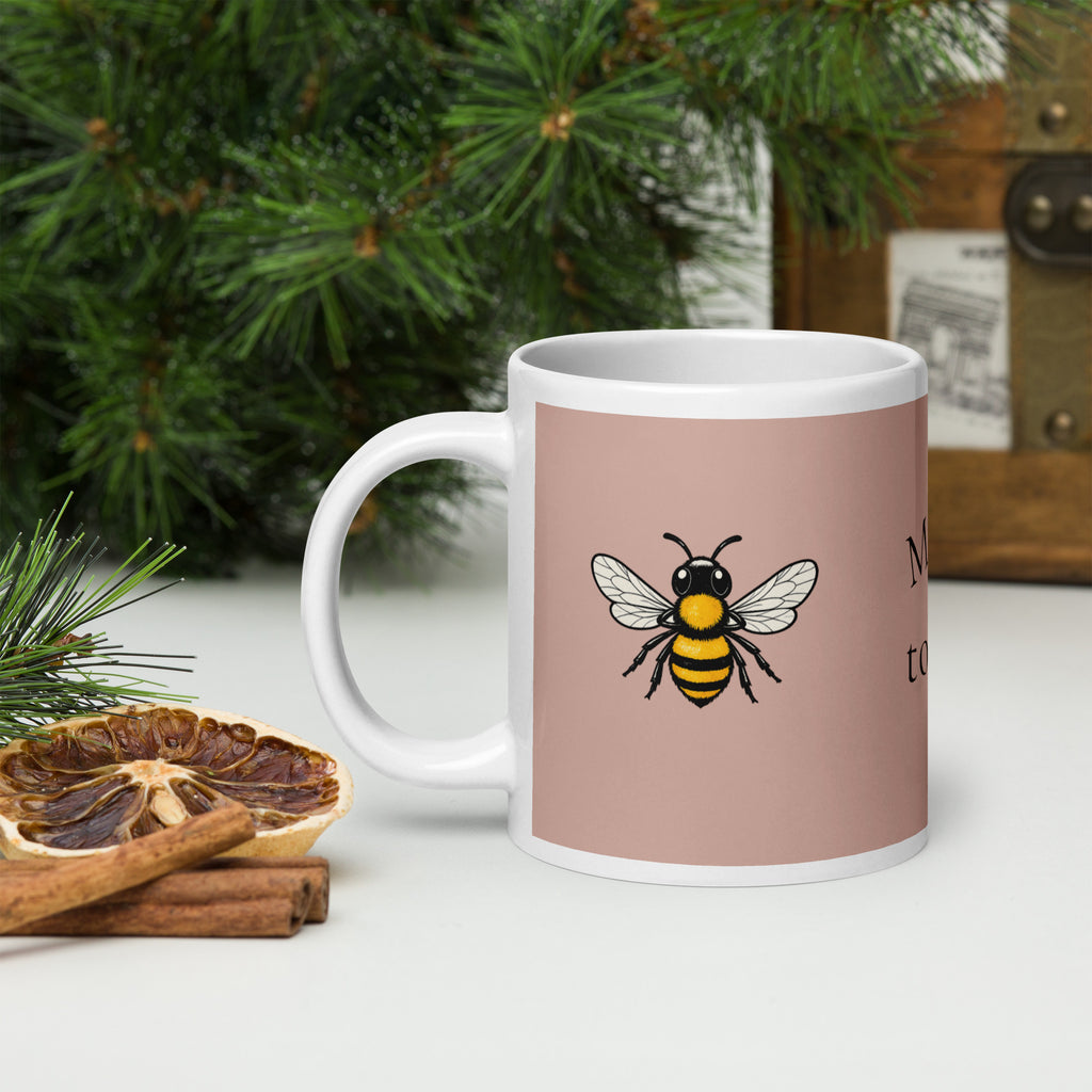 Dusty rose ceramic coffee mug with bee illustration, shown in side angle.