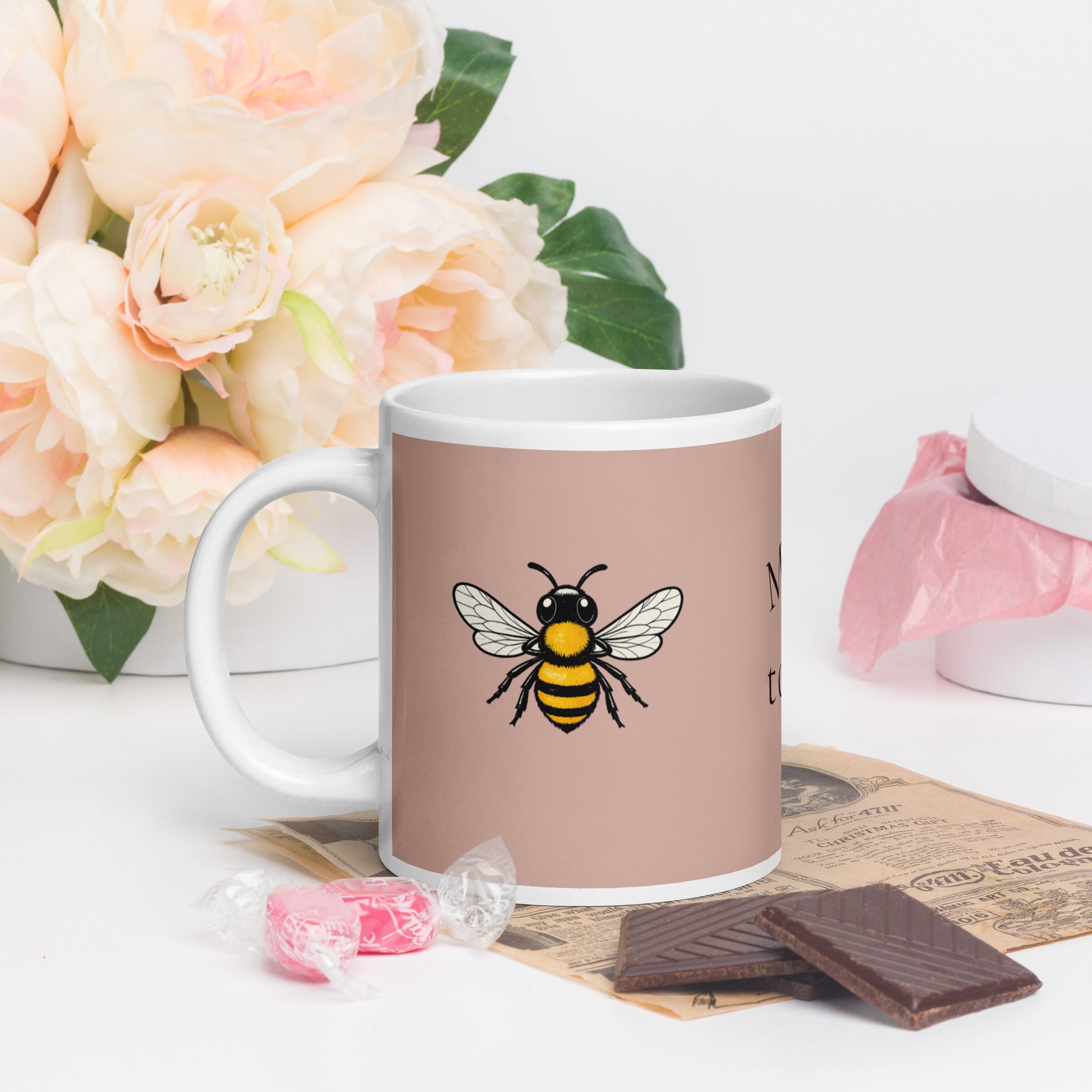 Dusty rose ceramic coffee mug with bee illustration, front view and white handle.