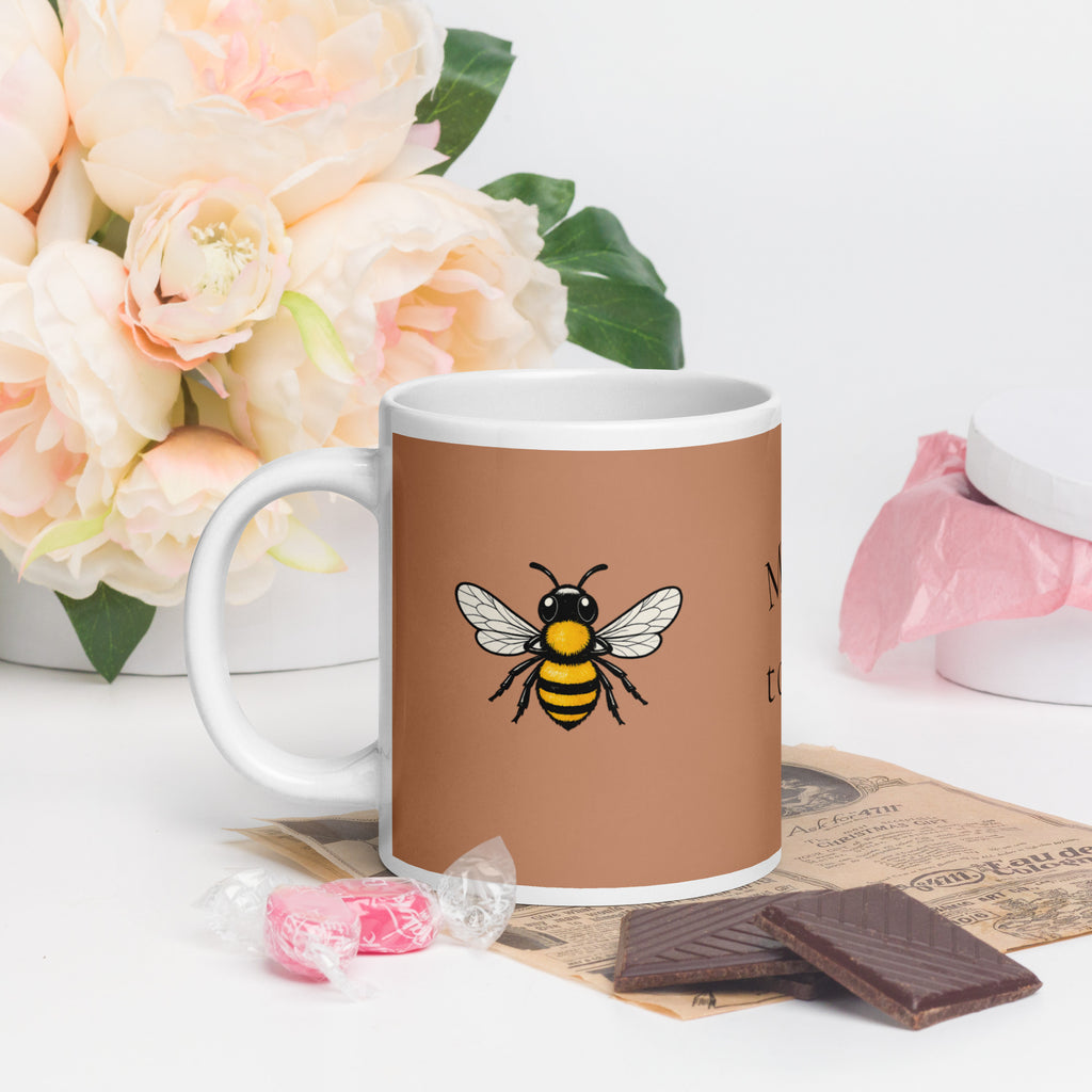 Brown ceramic coffee mug with bee illustration, white handle and top rim