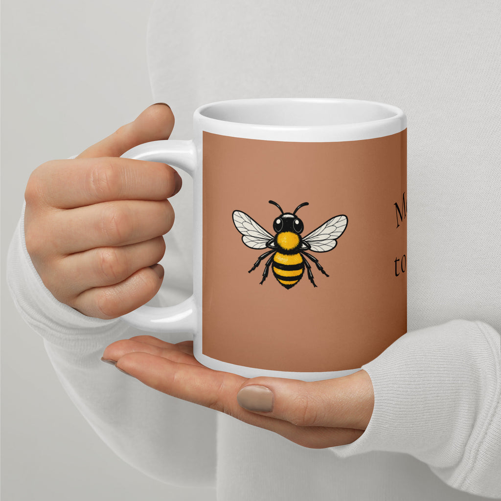 Brown ceramic mug with bee illustration, close-up grip on the handle by one hand.