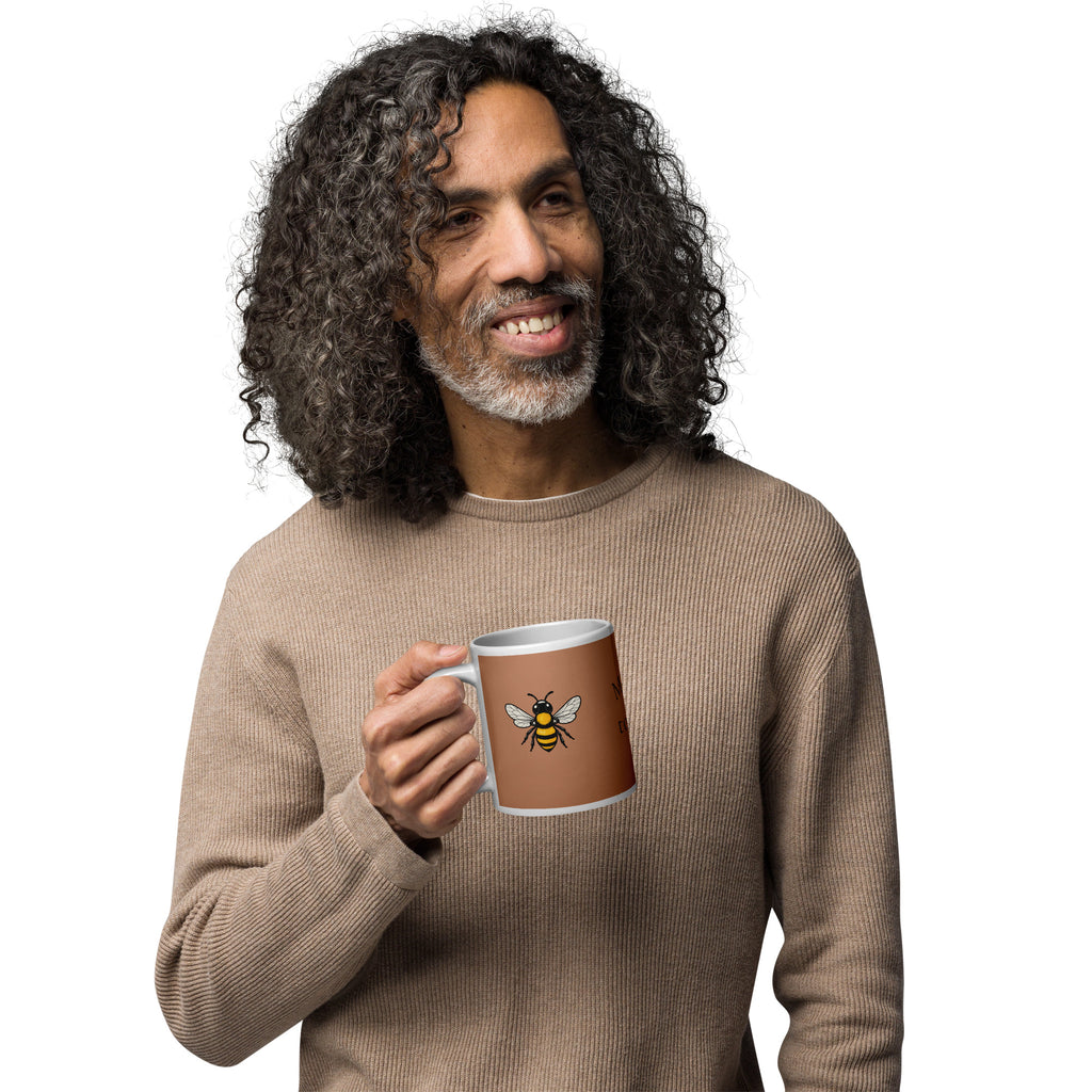 Brown ceramic coffee mug with bee illustration, held in hand