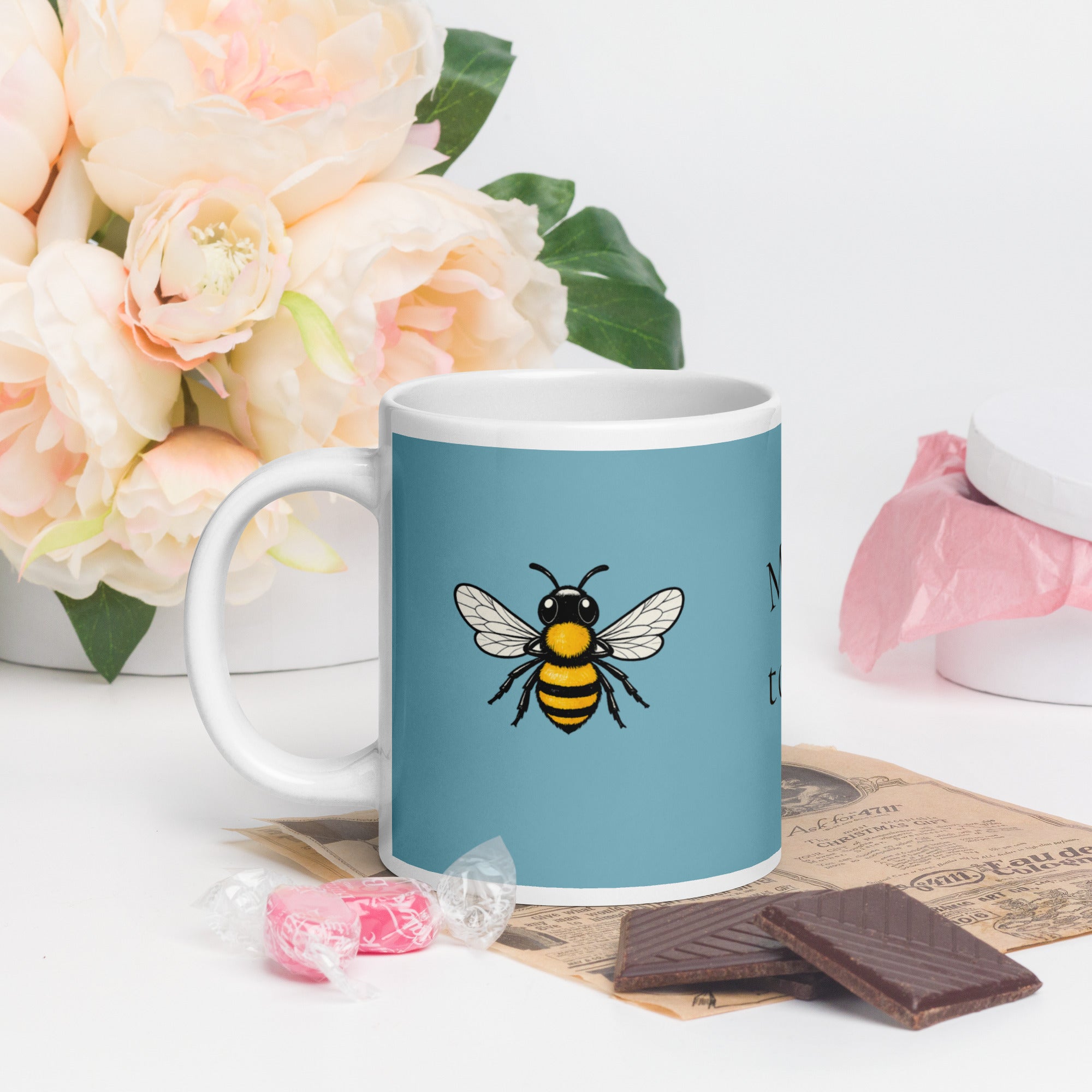 Blue ceramic mug with white rim and handle, large bee illustration on the front