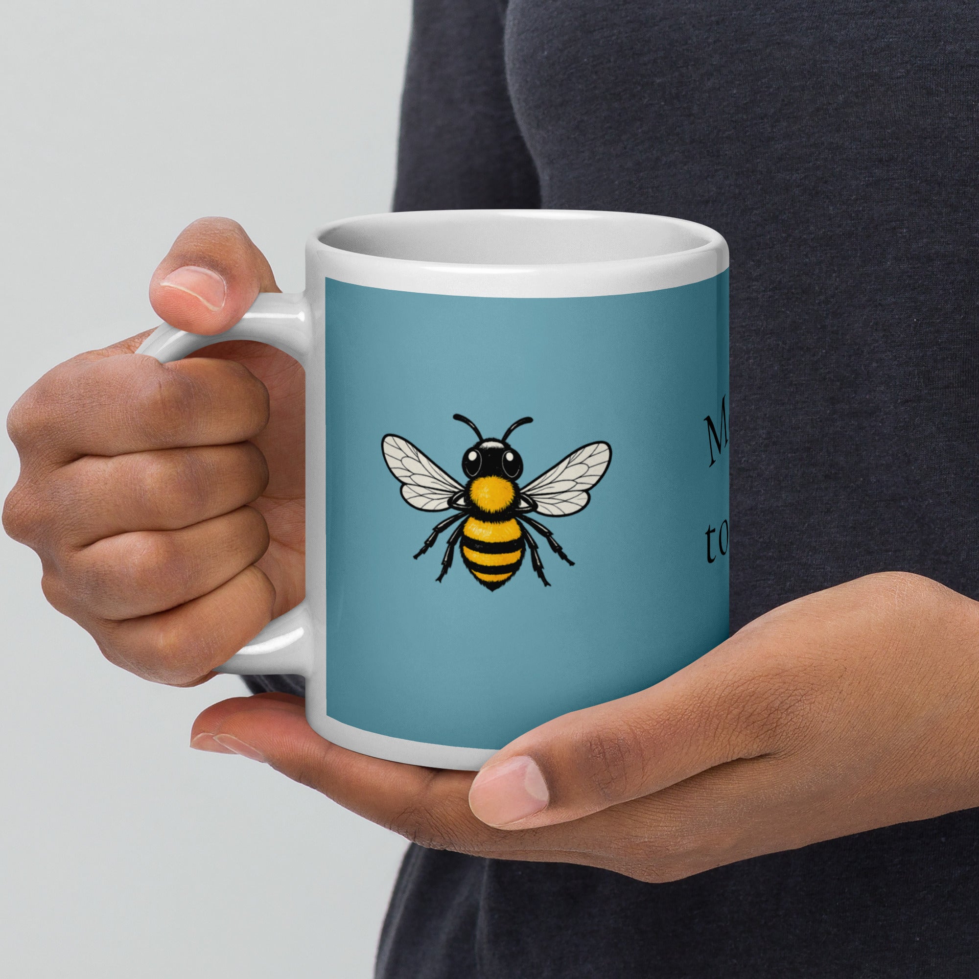 Blue ceramic mug with white rim and handle, bee illustration shown while held