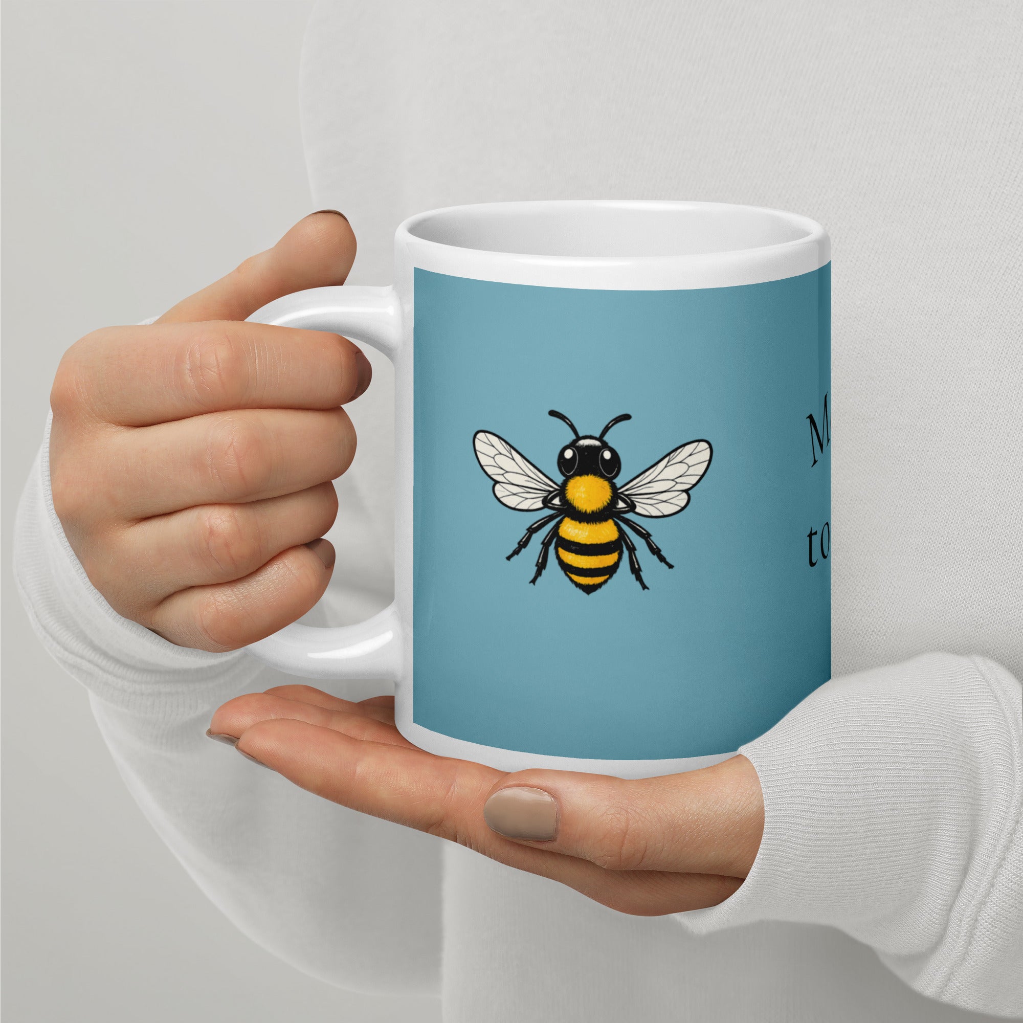 Blue ceramic coffee mug with centered bee illustration on front, white rim and handle