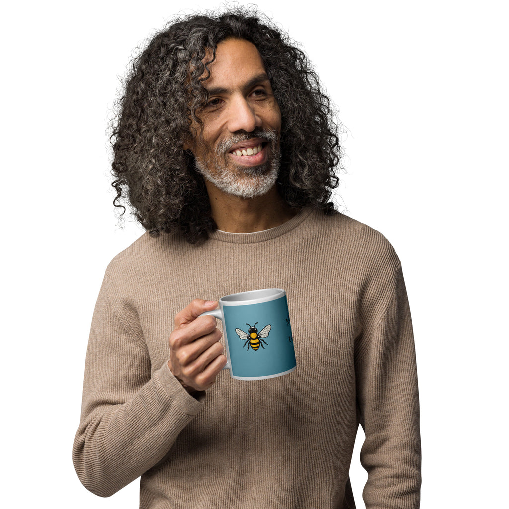 Blue ceramic coffee mug with bee illustration centered, white rim and handle