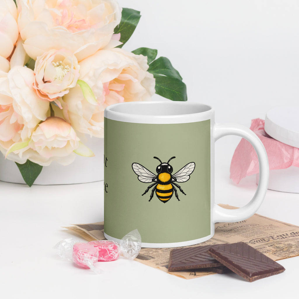 Sage green ceramic mug with white handle and bee illustration on front
