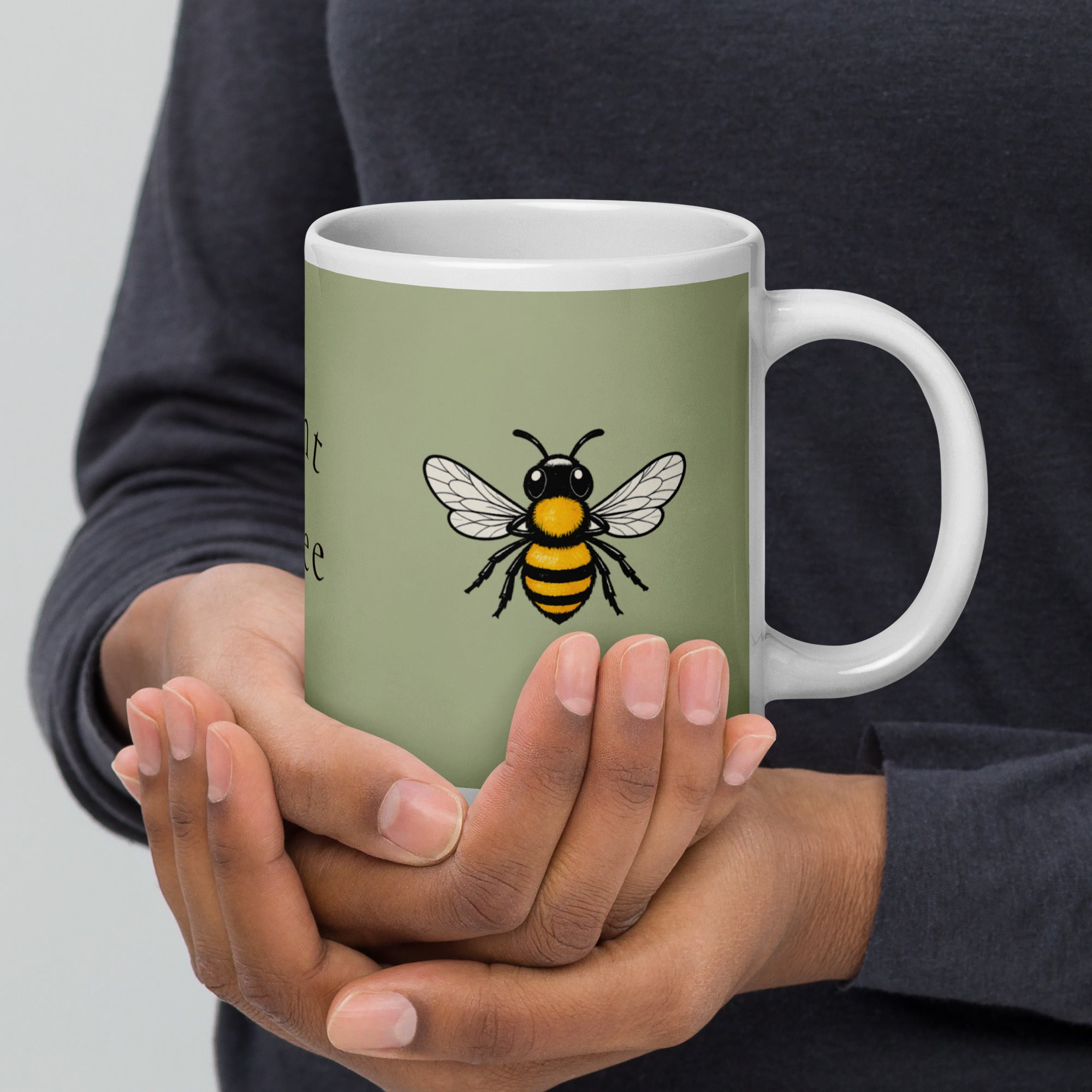 Sage green ceramic coffee mug held in hands with white handle and bee illustration