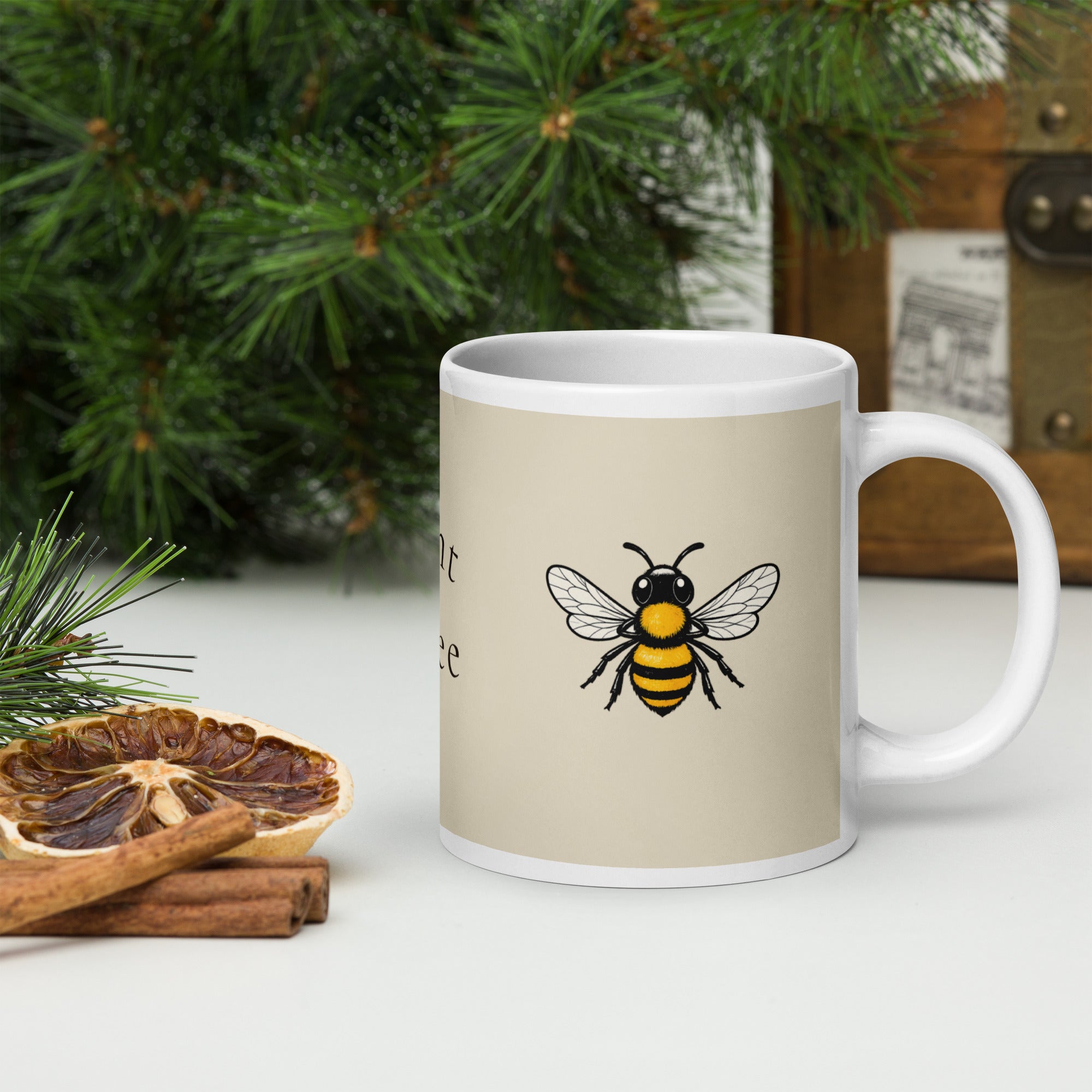 Light beige ceramic coffee mug with white handle and bee illustration near center