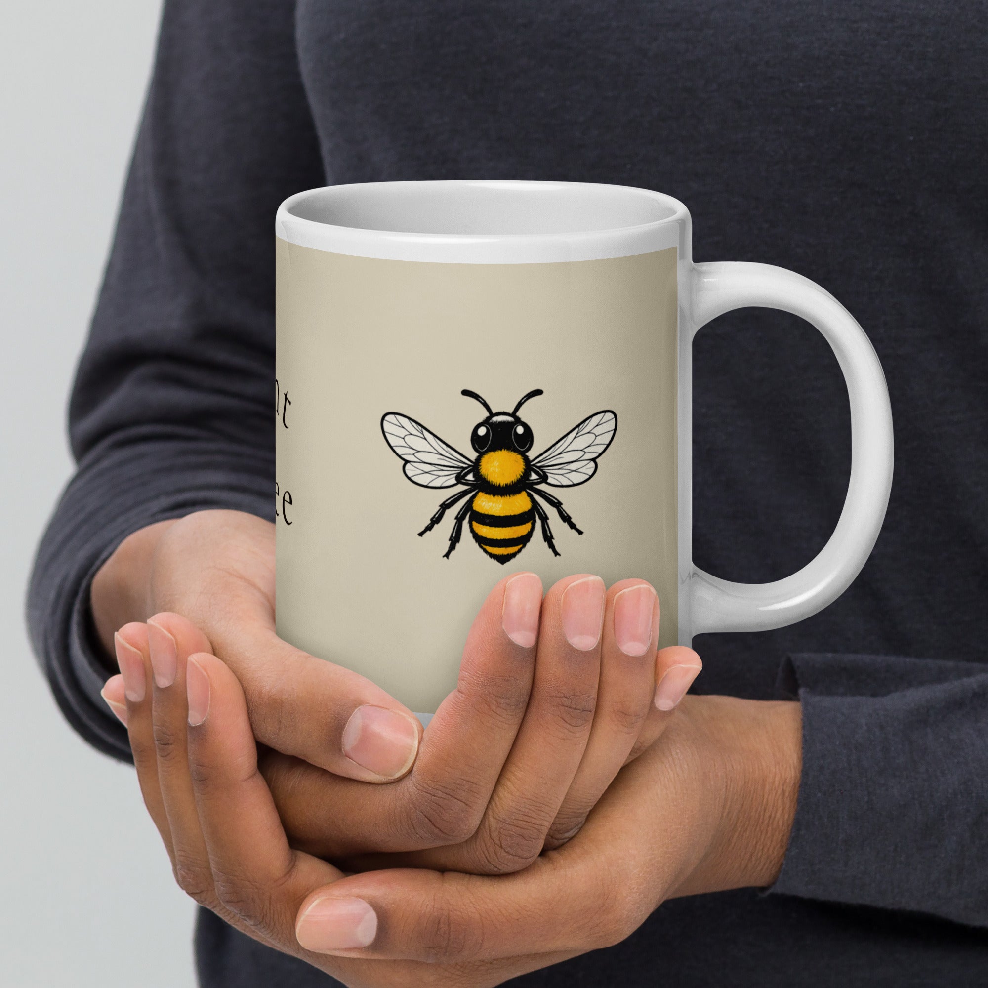 Light beige ceramic coffee mug with white handle, bee illustration in center