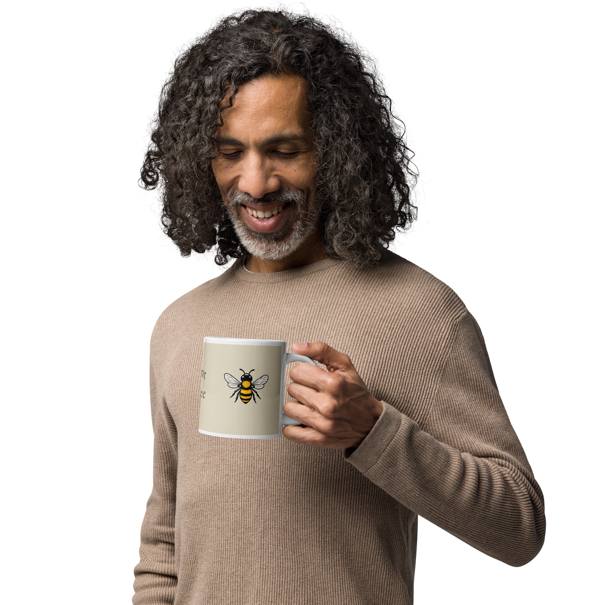 Light beige ceramic coffee mug with bee illustration, held near face