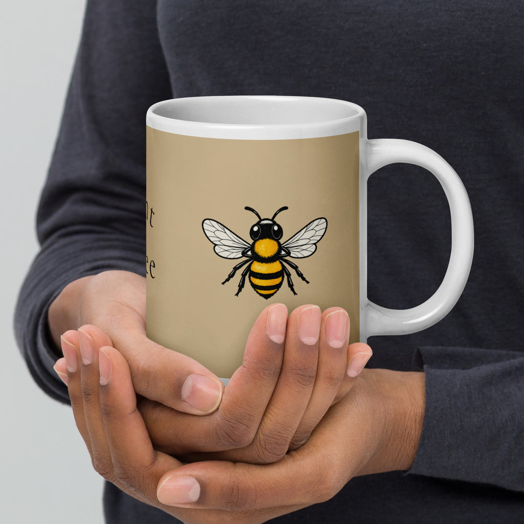 Beige ceramic coffee mug with white handle, bee illustration visible on the front