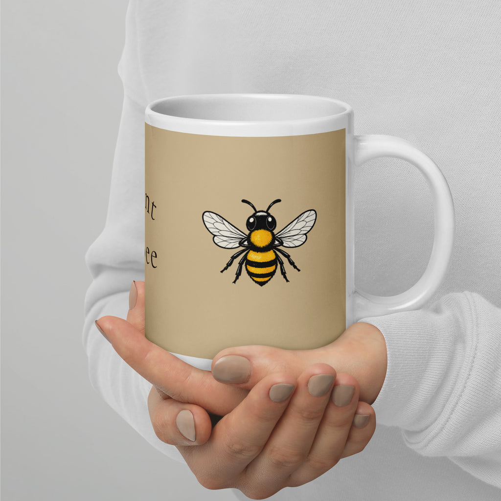 Beige ceramic mug with white handle and rim, yellow-and-black bee illustration on front