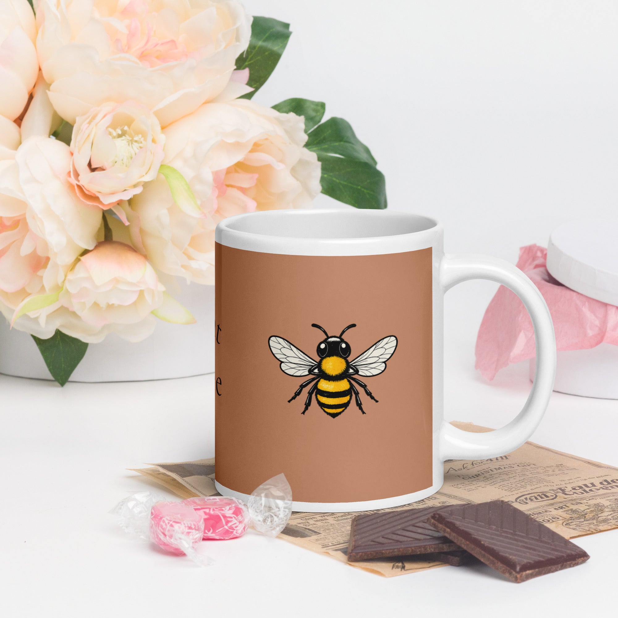 Brown ceramic coffee mug with bee illustration, white handle and curved body
