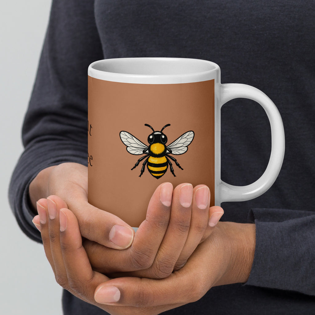 Brown ceramic mug with bee illustration and white handle, held by two hands