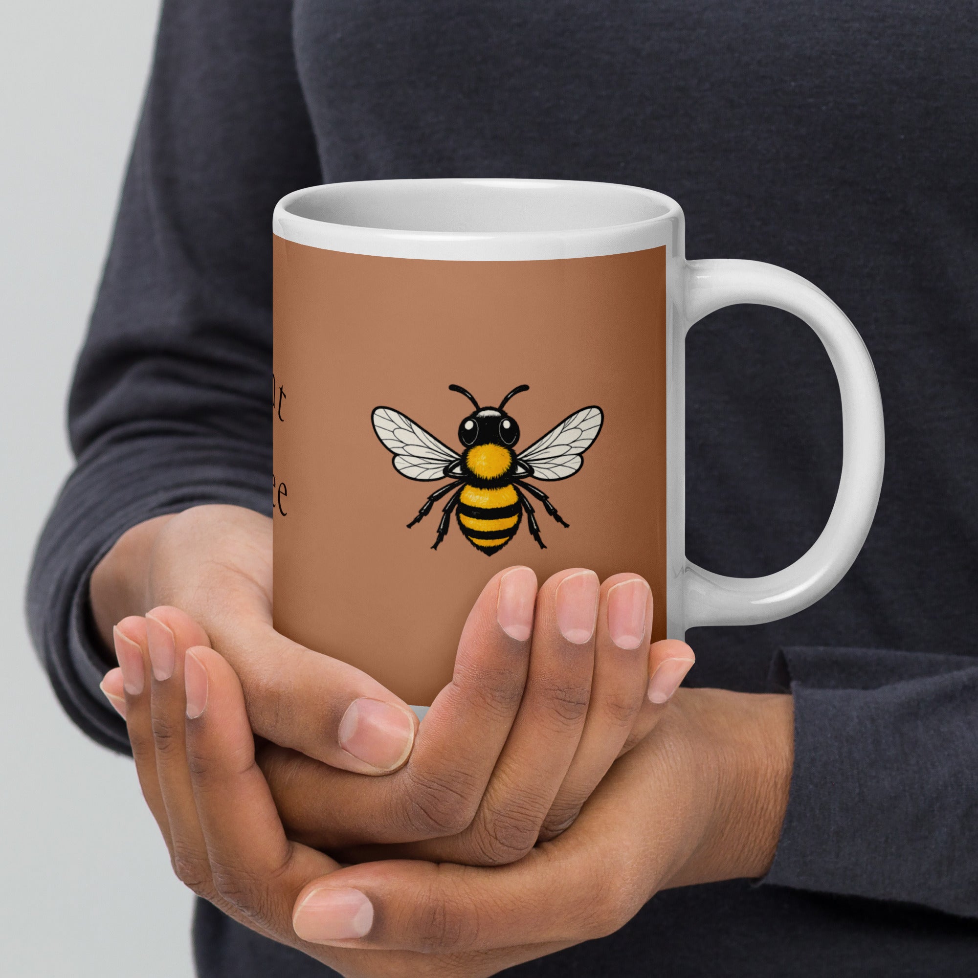Brown ceramic mug with bee illustration and white handle, held by two hands