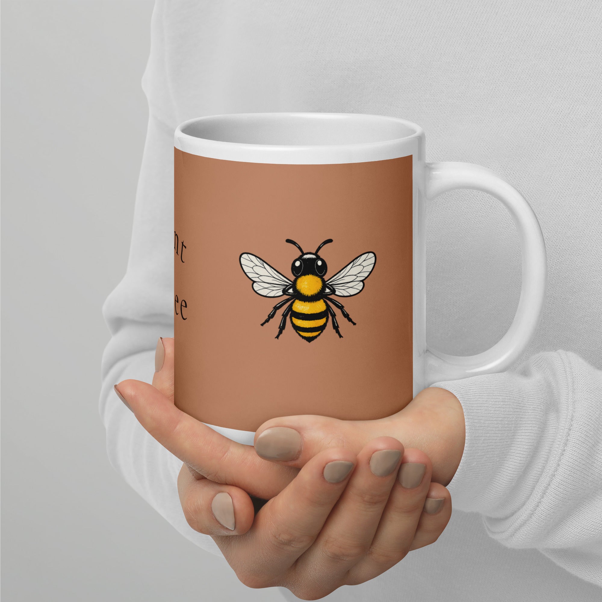 Brown ceramic mug with bee illustration, front view held by hands with gray nail polish.