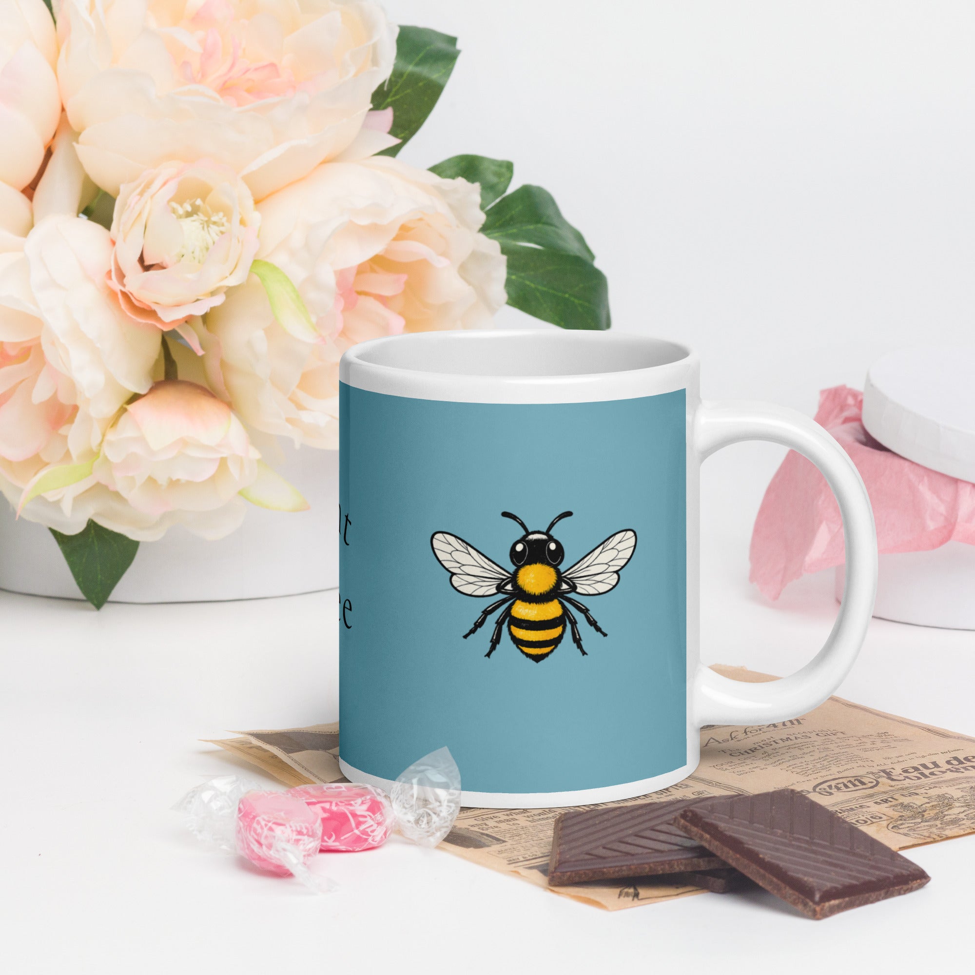 Blue ceramic mug with white rim and handle, bee illustration centered on the front