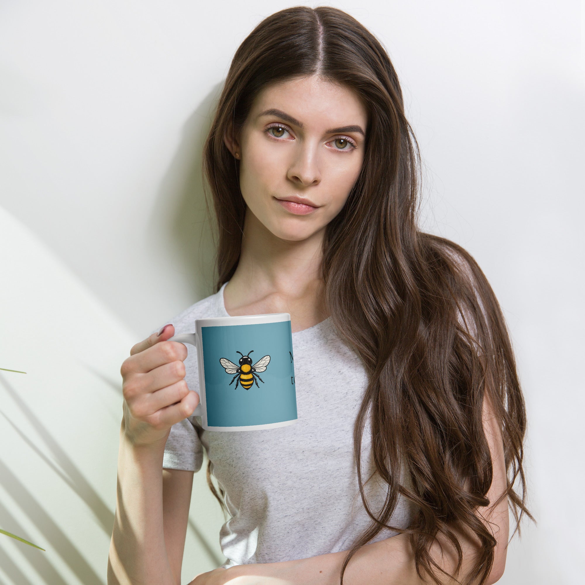 Person holding a blue ceramic coffee mug with bee illustration